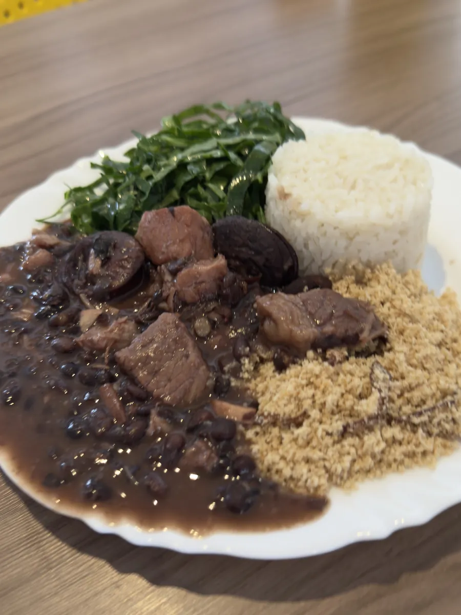 Prato de feijoada com arroz, couve e farofa servido no Brasas e Fogão